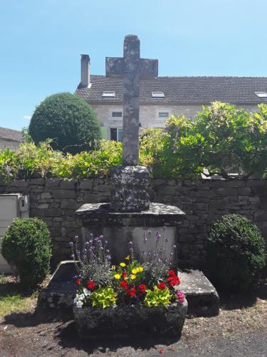 a cross in the middle of a garden with flowers at Les Charmes du Lac in Esclauzels