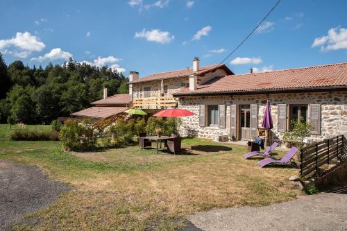 a house with a yard with chairs and an umbrella at Moulin des Comtes - Gite des Graines in Viverols