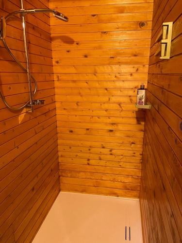 y baño con ducha y paredes de madera. en Dotik gozda, en Železniki