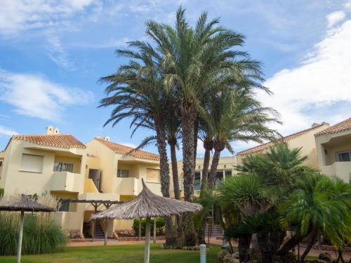 a group of palm trees in front of a building at Aparthotel Villas La Manga in La Manga del Mar Menor