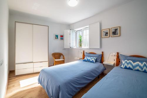 1 dormitorio con 2 camas con sábanas azules y ventana en Villa Kabanita, en Tazacorte