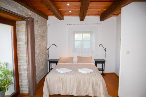 a bedroom with a bed and a brick wall at Somos Apartman in Győr