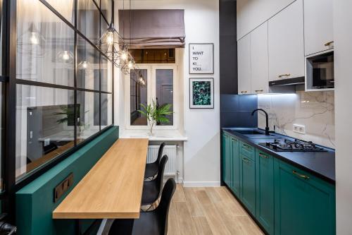 利維夫的住宿－Emerald Lux Apartment. LiveInLviv，厨房配有绿色橱柜和木桌