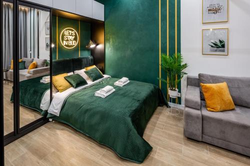 a bedroom with a green bed and a couch at Emerald Lux Apartment. LiveInLviv in Lviv