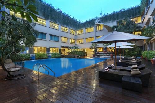 a hotel pool with chairs and an umbrella at favehotel Premier Cihampelas in Bandung