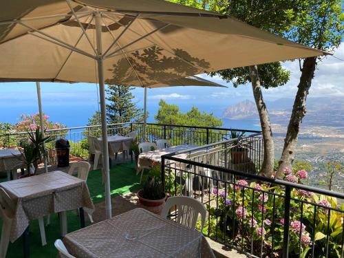 a patio with tables and chairs and an umbrella at Hotel Villa San Giovanni in Erice