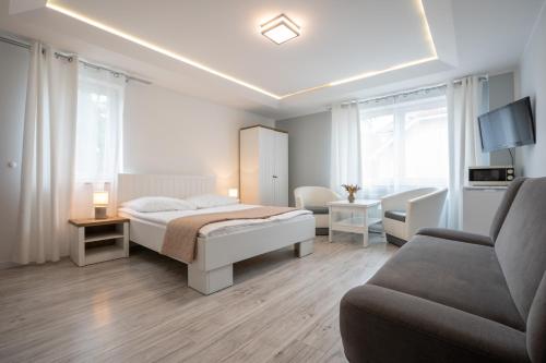 a white bedroom with a bed and a couch at Pablo in Niechorze
