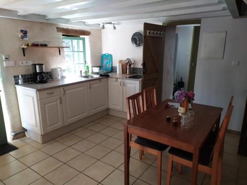 une cuisine avec une table en bois et une table et des chaises dans l'établissement Ar Parkou, à Plonévez-du-Faou