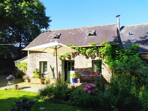 une maison en pierre avec un parasol dans la cour dans l'établissement Ar Parkou, à Plonévez-du-Faou