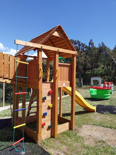 een houten speelstructuur met een ladder en een glijbaan bij Camping TIKITI in Propriano