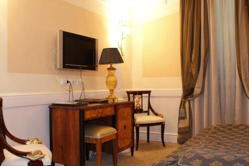 um quarto de hotel com uma secretária, uma televisão e uma cama em Boutique Hotel Trevi em Roma