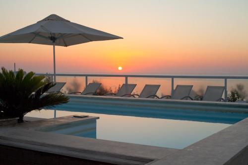 a pool with chairs and an umbrella and the sunset at The George, Urban Boutique Hotel in St Julian's