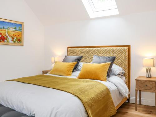 a bedroom with a large bed with yellow pillows at Stables Cottage in Heathfield