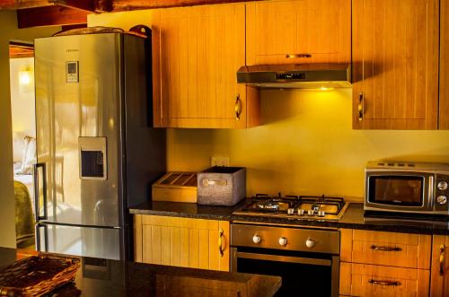 a kitchen with wooden cabinets and a stainless steel refrigerator at Tshikwalo Game Lodge in Klipdrift