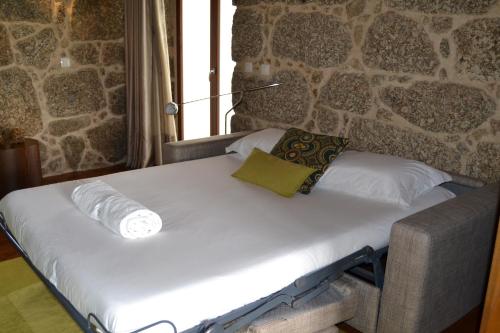 a bed in a room with a stone wall at Quinta do Medronheiro Hotel Rural in Viseu