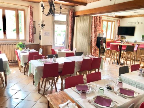 a restaurant with white tables and red chairs at Le Sans Souci in Jausiers