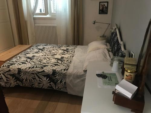 a bed with a black and white blanket and a table at camera con bagno privato e parcheggio in Lucca