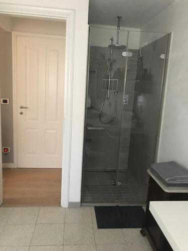 La salle de bains est pourvue d'une douche avec une porte en verre. dans l'établissement camera con bagno privato e parcheggio, à Lucques