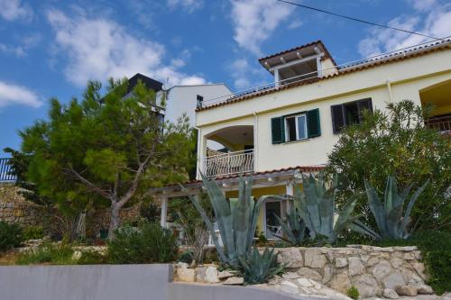 a large house with green shutters and trees at Apartman Rosa 2 in Kustići