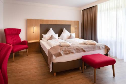 a bedroom with a large bed and two red chairs at Appartment Hotel Victoria in Bad Füssing