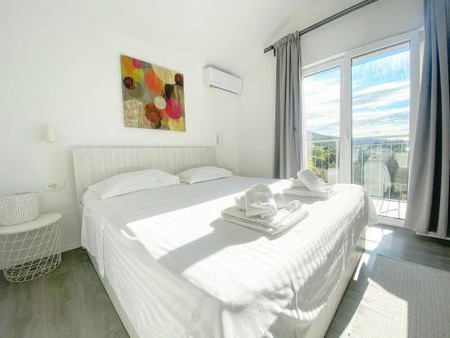 - une chambre blanche avec un grand lit blanc et une fenêtre dans l'établissement Apartment Larum, à Zavala