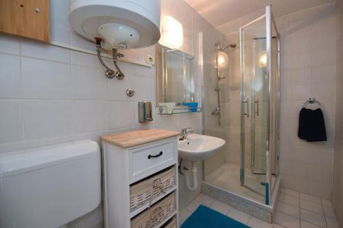 a white bathroom with a sink and a shower at Apartman Rosa 2 in Kustići