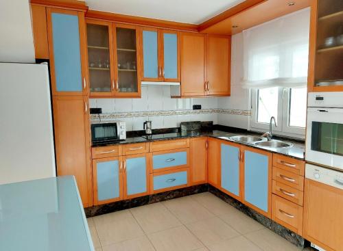 una cocina con armarios de madera y fregadero en Casa Sueño, en Foz