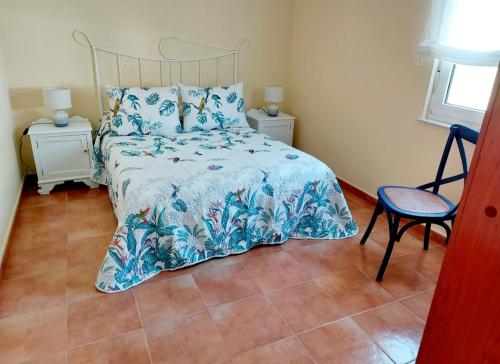 a bedroom with a bed with a blue bedspread and a chair at Casa Sueño in Foz