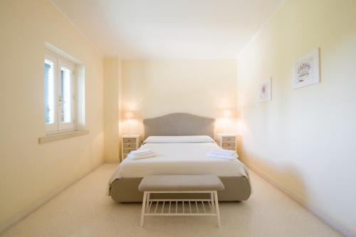 una camera bianca con un letto e uno sgabello di Parco Degli Aranci a Cutrofiano