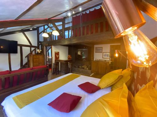 - une chambre dotée d'un grand lit avec des oreillers rouges et jaunes dans l'établissement Le Relais Du Haras - Deauville, à Touques