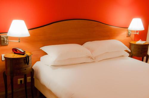 a bedroom with a bed with white pillows and a red wall at Hotel Eden Montmartre in Paris