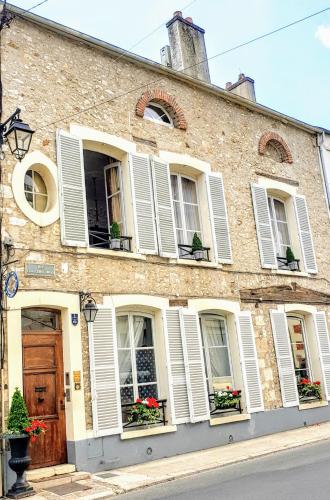 a building with white shutters and flowers in windows at Royal Hubert in Provins