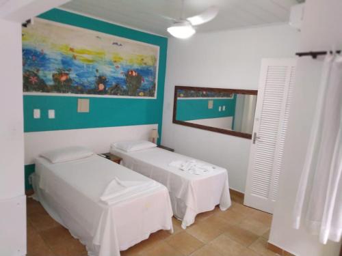 a room with two beds and a mirror at Pousada Vison in Ubatuba