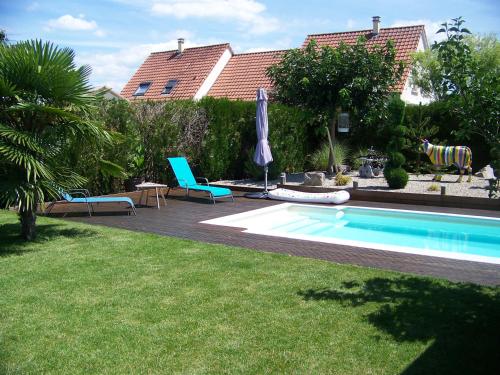 une piscine avec deux chaises et un parasol dans l'établissement C' 1 comble, à Bischwihr