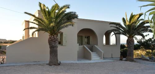 duas palmeiras em frente a uma casa branca em Olive Villa em Kamari
