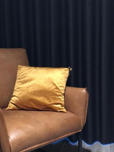 a yellow pillow sitting on top of a leather chair at De Konik in Uikhoven