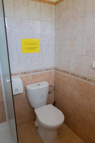 a bathroom with a toilet and a yellow sign on the wall at Penzion Štekrův Mlýn in Františkovy Lázně