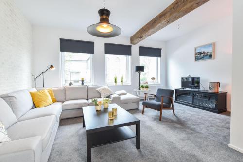 a living room with a white couch and a table at Royaal appartement in het centrum van Yerseke in Yerseke