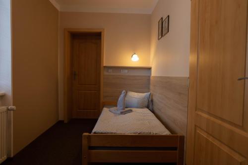 a small room with a bed with a light on the wall at Penzion Štekrův Mlýn in Františkovy Lázně