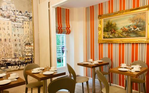 a restaurant with tables and chairs and a painting on the wall at Hotel Eden Montmartre in Paris