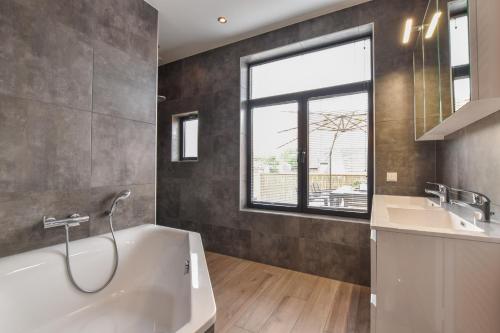 baño con bañera, lavabo y ventana en Royaal appartement in het centrum van Yerseke, en Yerseke