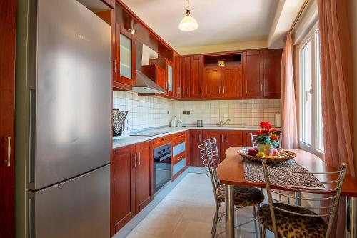 a kitchen with wooden cabinets and a table and a refrigerator at MariZot Apartment in Alexandroupoli