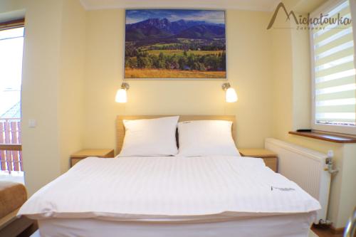 a bedroom with a white bed and a painting on the wall at Willa Michałówka in Zakopane