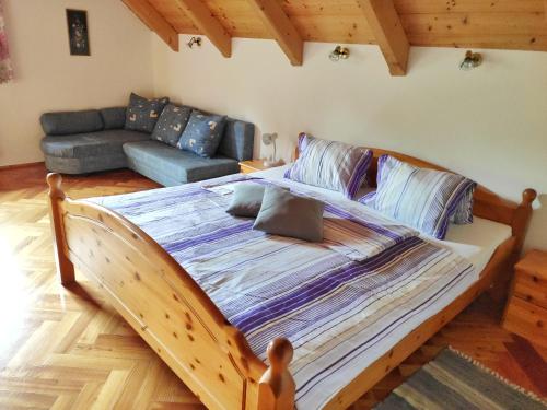 un grande letto in legno in una camera con divano di Gästehaus Laßnig a Ebene Reichenau