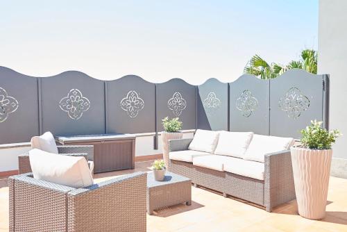 a patio with wicker chairs and couches and a fence at Una Chicca a Roma in Rome