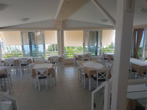 a restaurant with white tables and chairs and windows at KOSTA MARIA in Paleros