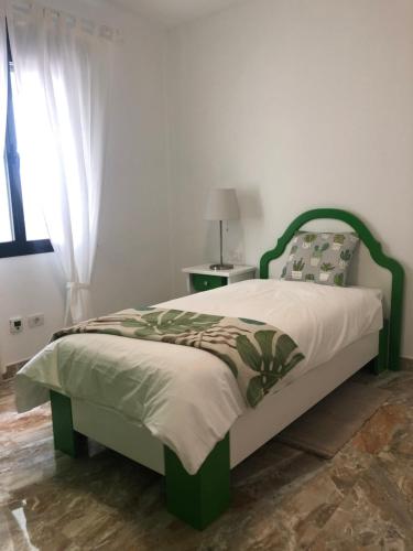 een bed met een groen hoofdeinde in een slaapkamer bij Luján 2 B “entre campo y ciudad” in Puntallana