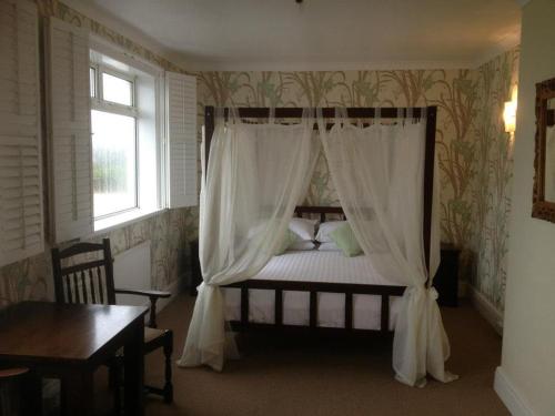 a bedroom with a canopy bed with white curtains at The Moorland Hotel in Wotter