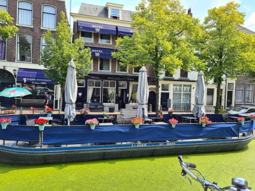 a blue boat with umbrellas on a river at Hotel Bridges House - Delft City Centre in Delft