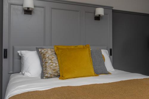 a bed with a yellow pillow and pillows on it at Marmalade in Portree